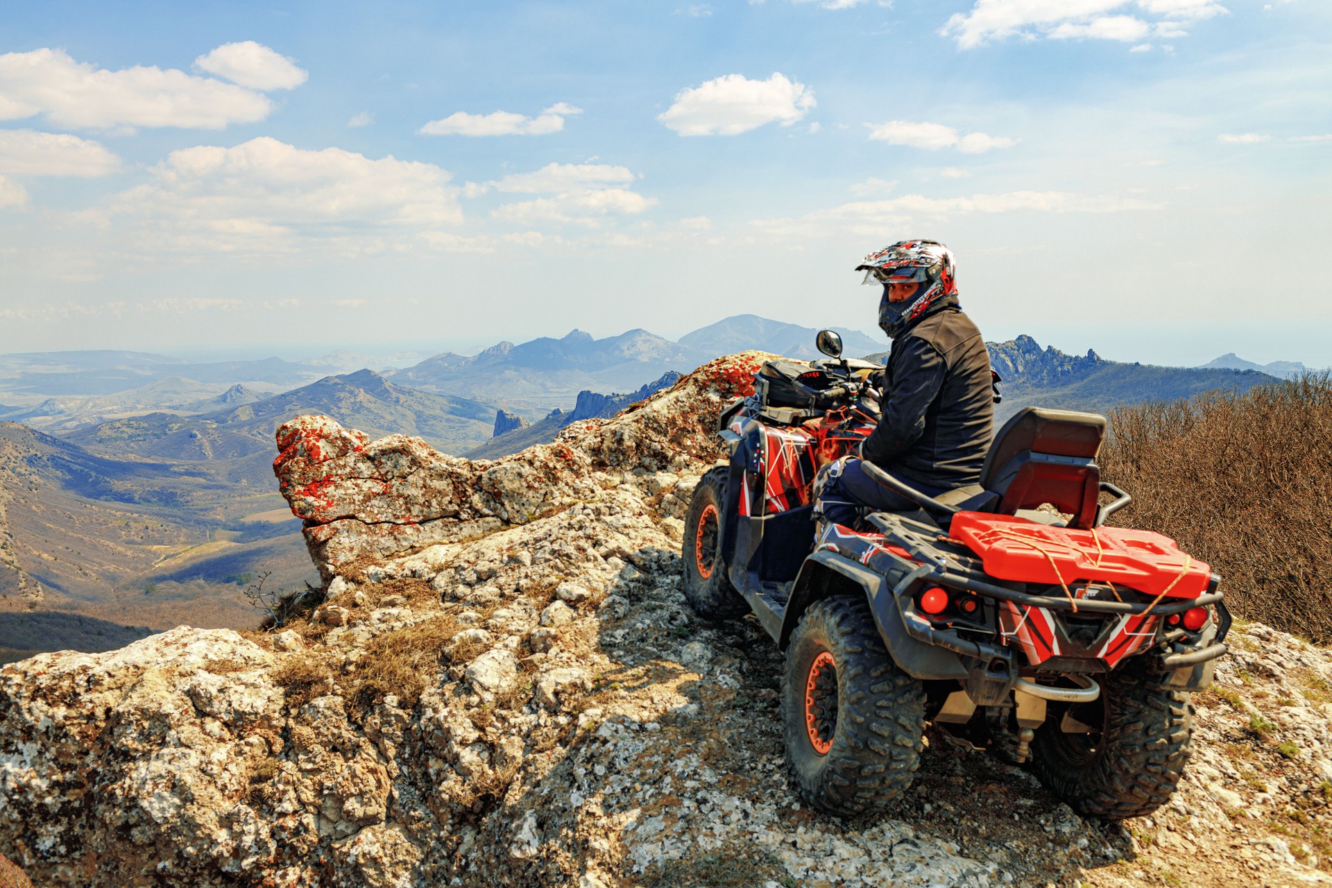 Man in helmet sitting on ATV quad bike in mountains